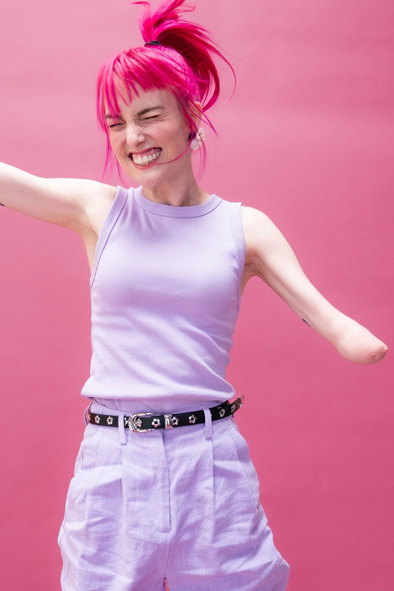 Madeleine is jumping around and smiling against a pink backdrop