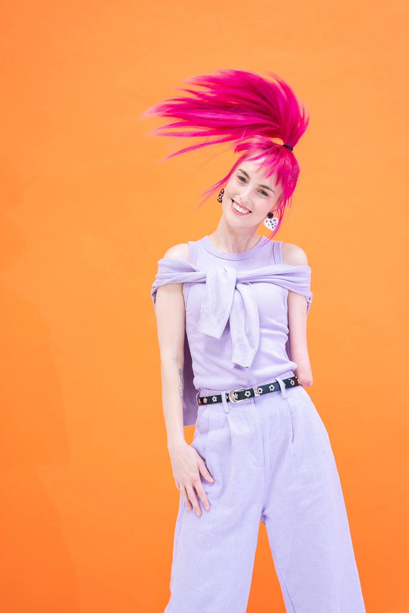 Madeleine tossing her hair in front of an orange backdrop