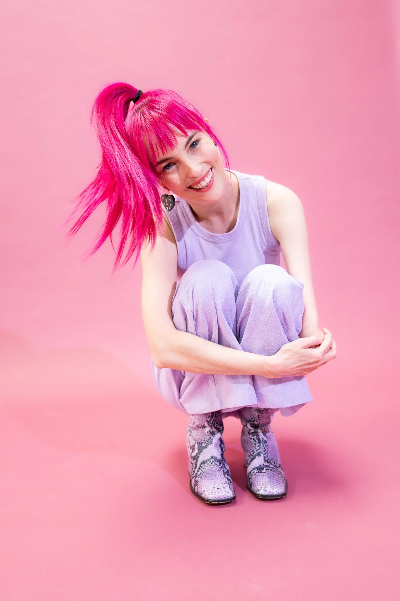 Madeleine sits crouched against a pink backdrop
