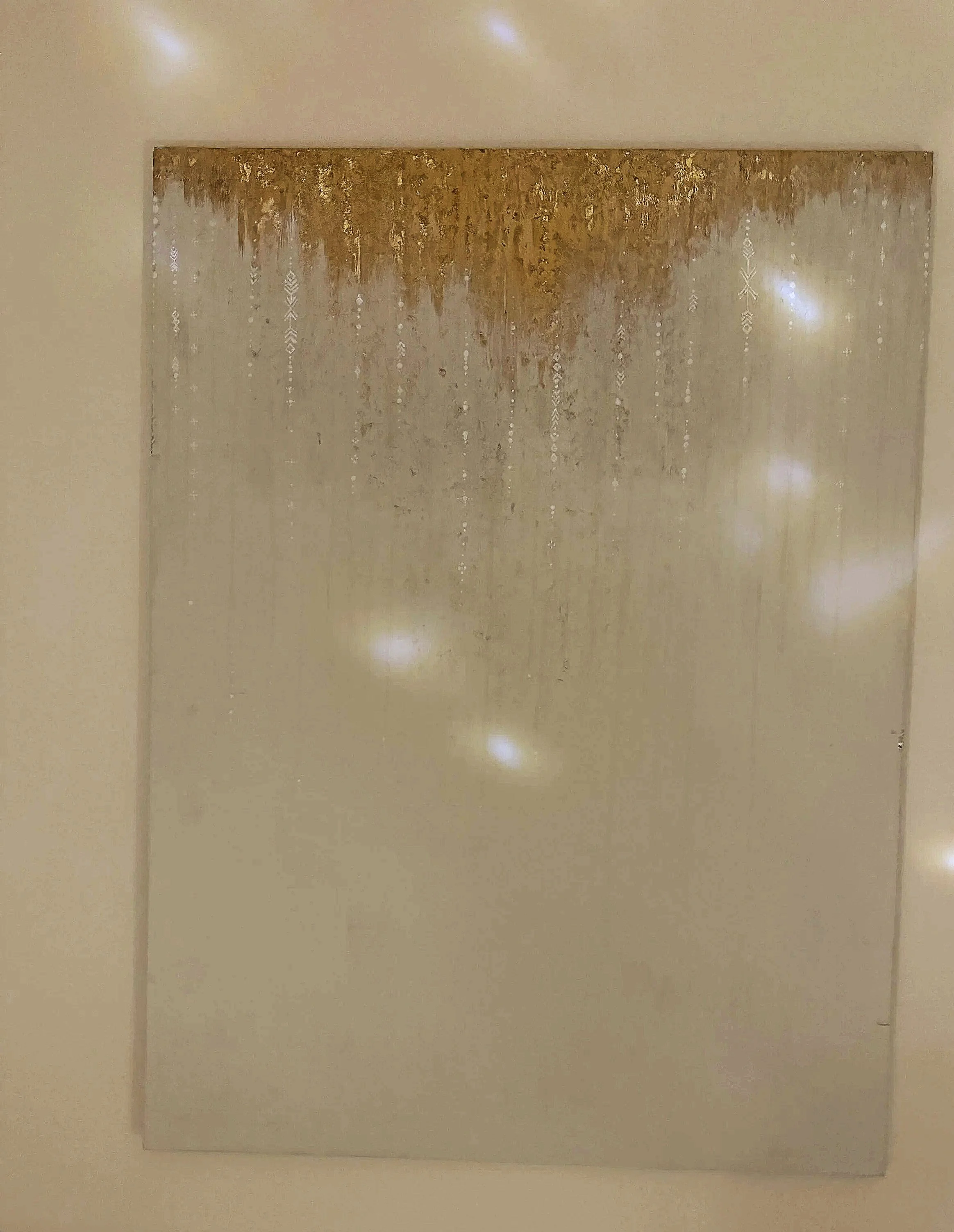 A decorative wall hanging with golden icicle-like patterns and geometric designs on a beige background.