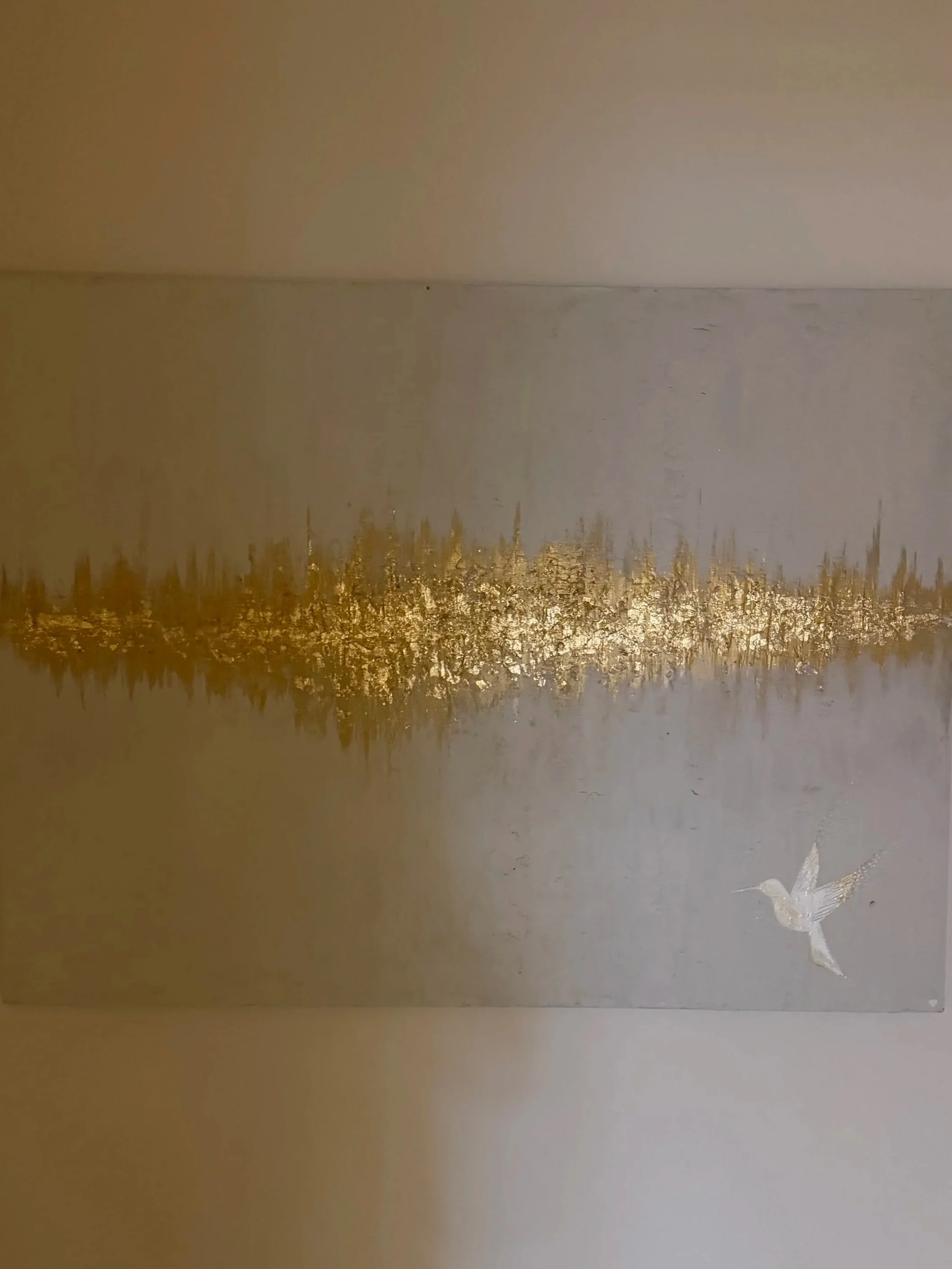 A white dragonfly flying near a body of water with trees in the background, reflecting in the water.