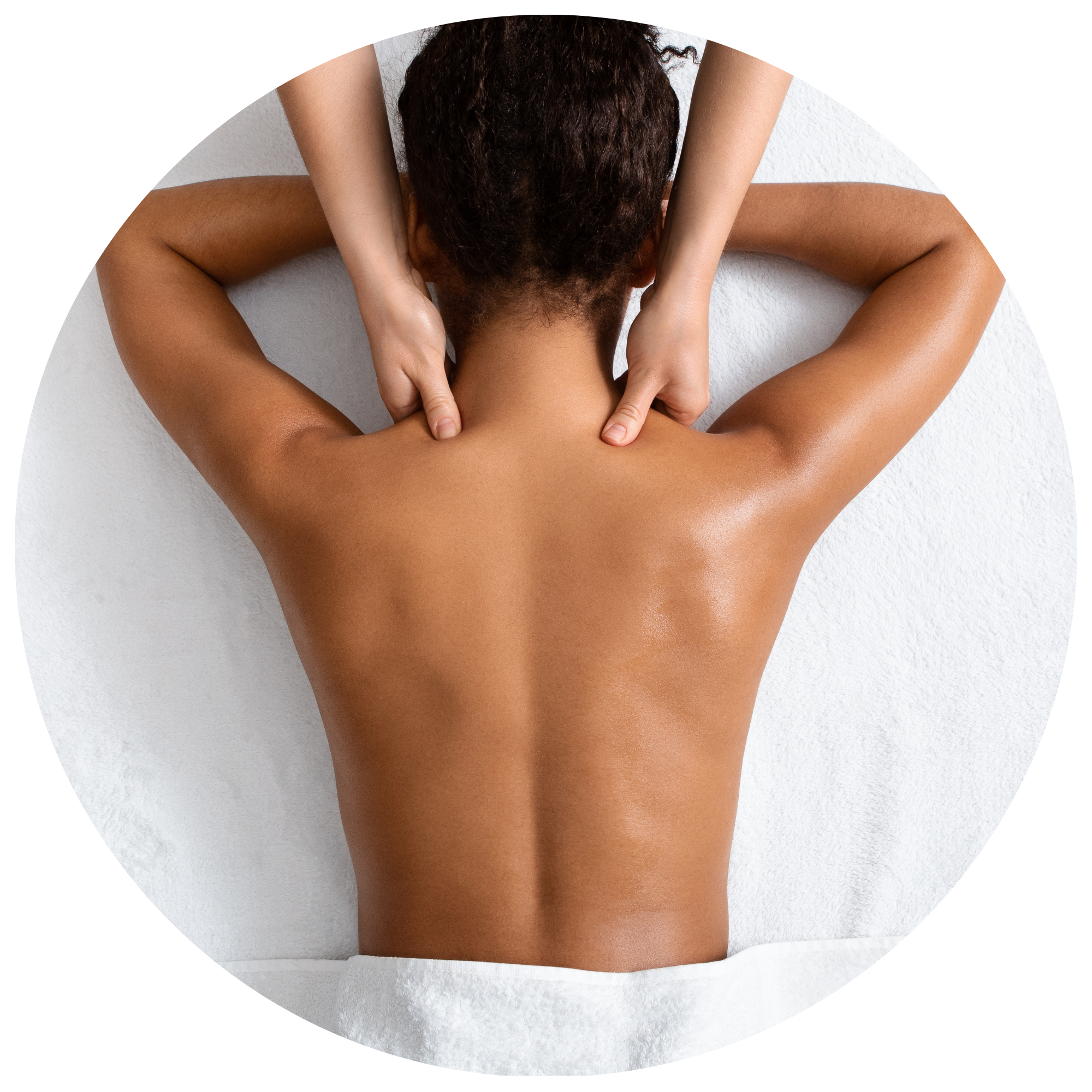 A person with short curly brown hair lying face down on a white surface with their hands behind their neck.
