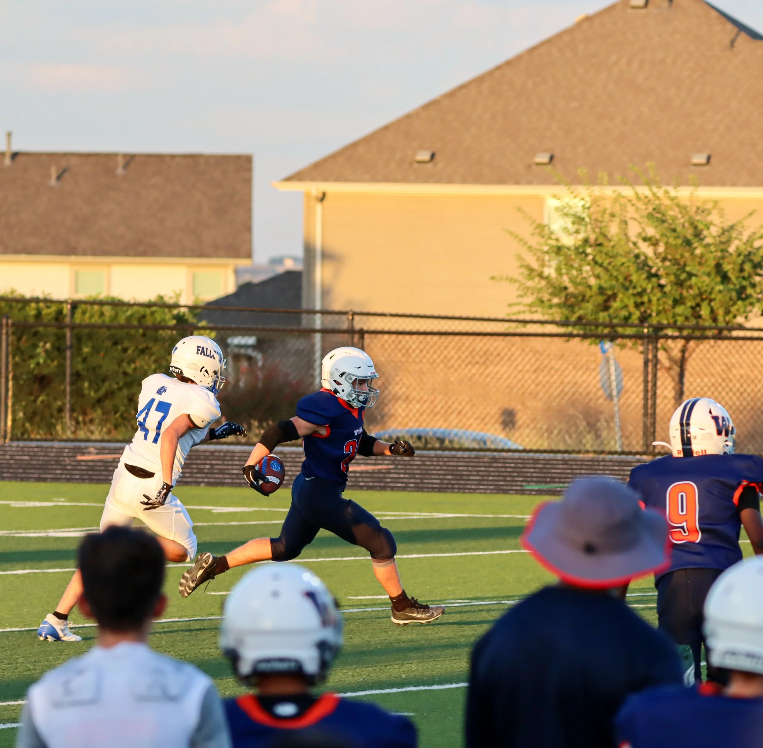 Children playing American football on a grassy field during daylight.