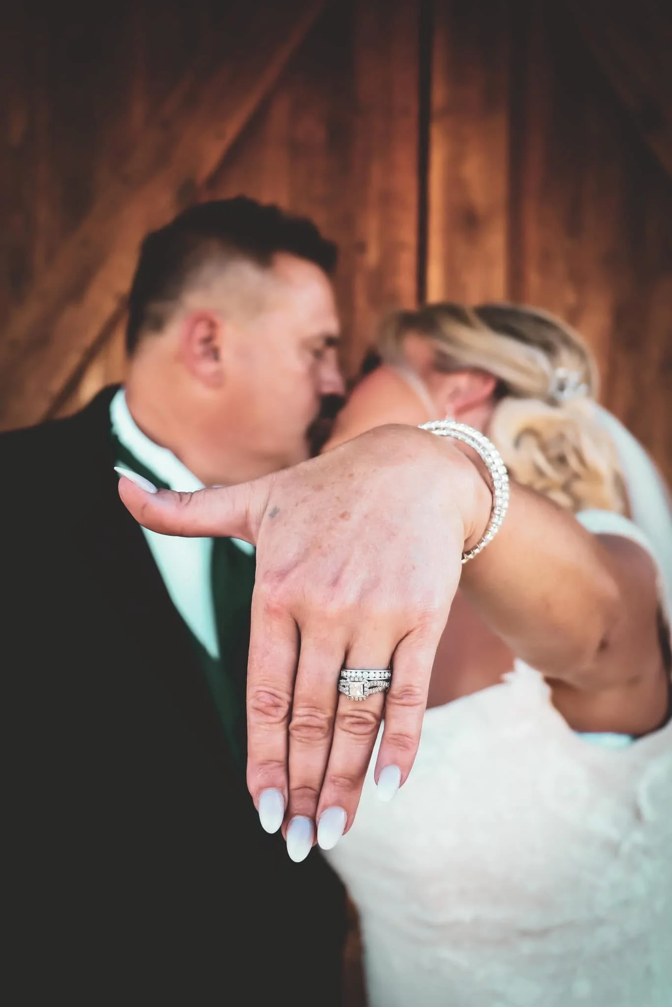Close-up of a wedding couple's hands showing their wedding rings, with their faces blurred in the background.