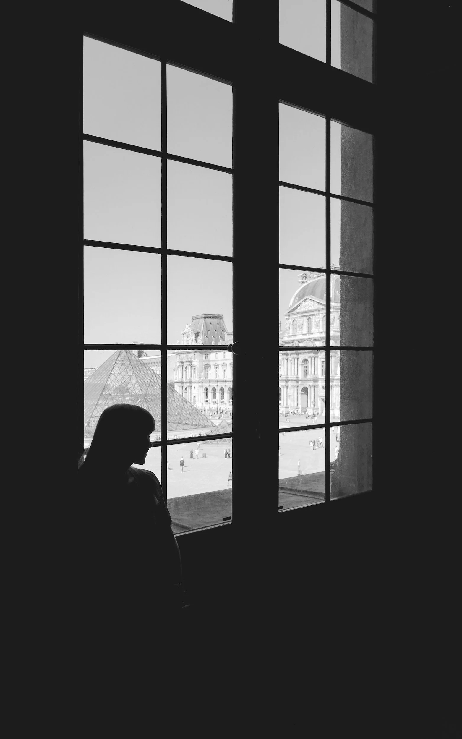 Black and white image of woman looking out the window.