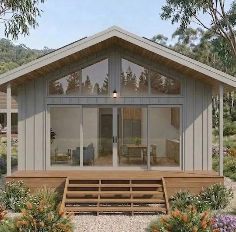 A modular dwelling with large glass sliding doors and pitched roof, set in a natural outdoor environment with trees and plants. 1 bedroom dwelling, granny flat, office, 2 bedroom dwelling, accommodation, AirBNB, cabin