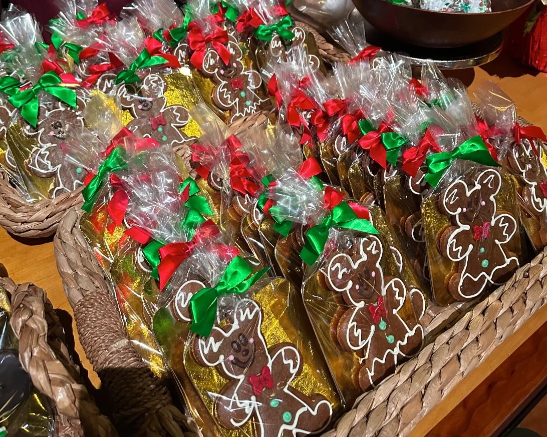 Gingerbread cookies wrapped in clear plastic bags with red and green bows, displayed in woven baskets.