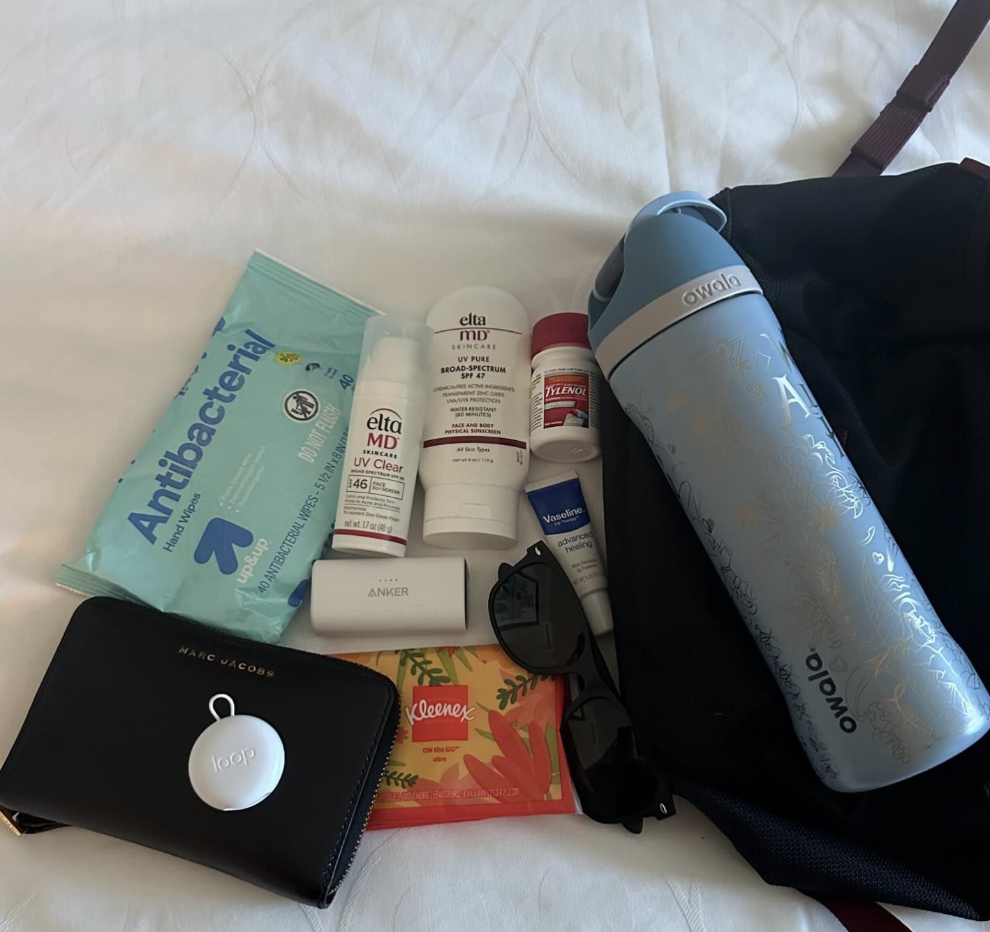 whats-in-my-bag-antibacterial-wipes-wallet-ear-plugs-elta-md-sunscreen-tylenol-kleenex-sunglasses-vaseline-water-bottle-and-black-bag-essentials-for-my-disneyland-days