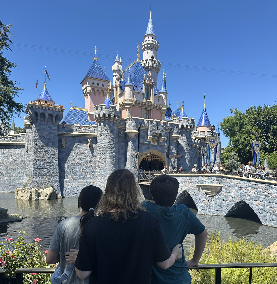 ugc-creator-kim-and-her-two-kids-a-boy-on-the-right-and-girl-on-the-left-of-kim-facing-sleeping-beautys-castle-at-disneyland