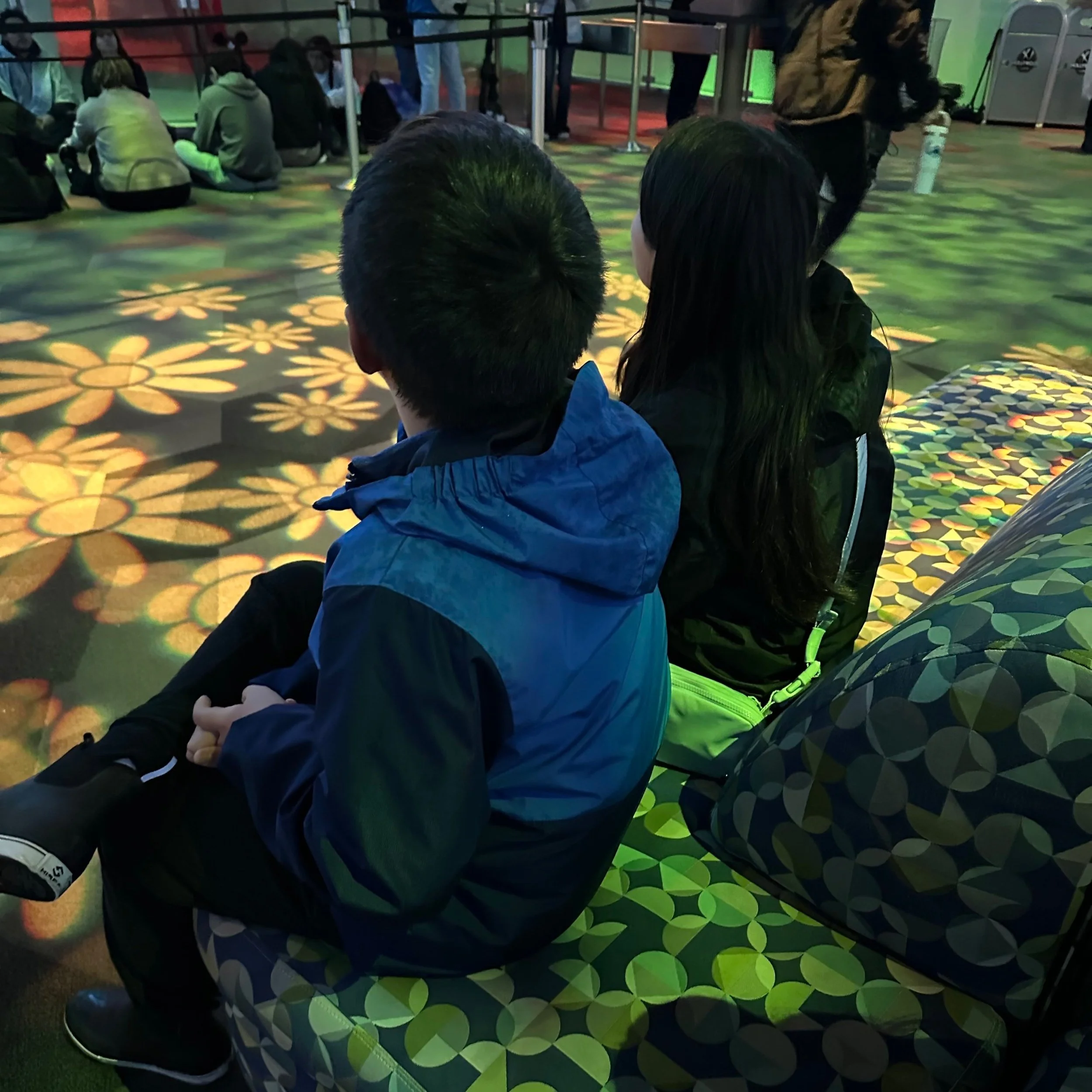 my-kids-son-and-daughter-sitting-inside-animation-academy-wearing-rain-jackets-waiting-out-rain-at-disneyland-california-adventure
