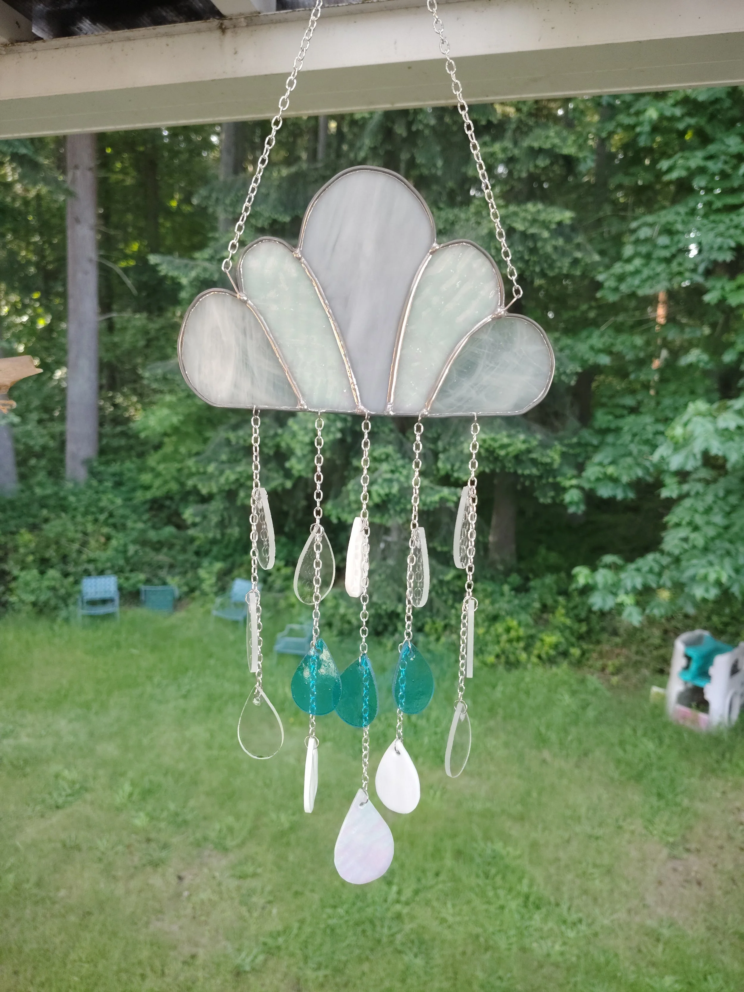 Stained glass cloud with multi colored drop hanging below that looks like raindrops