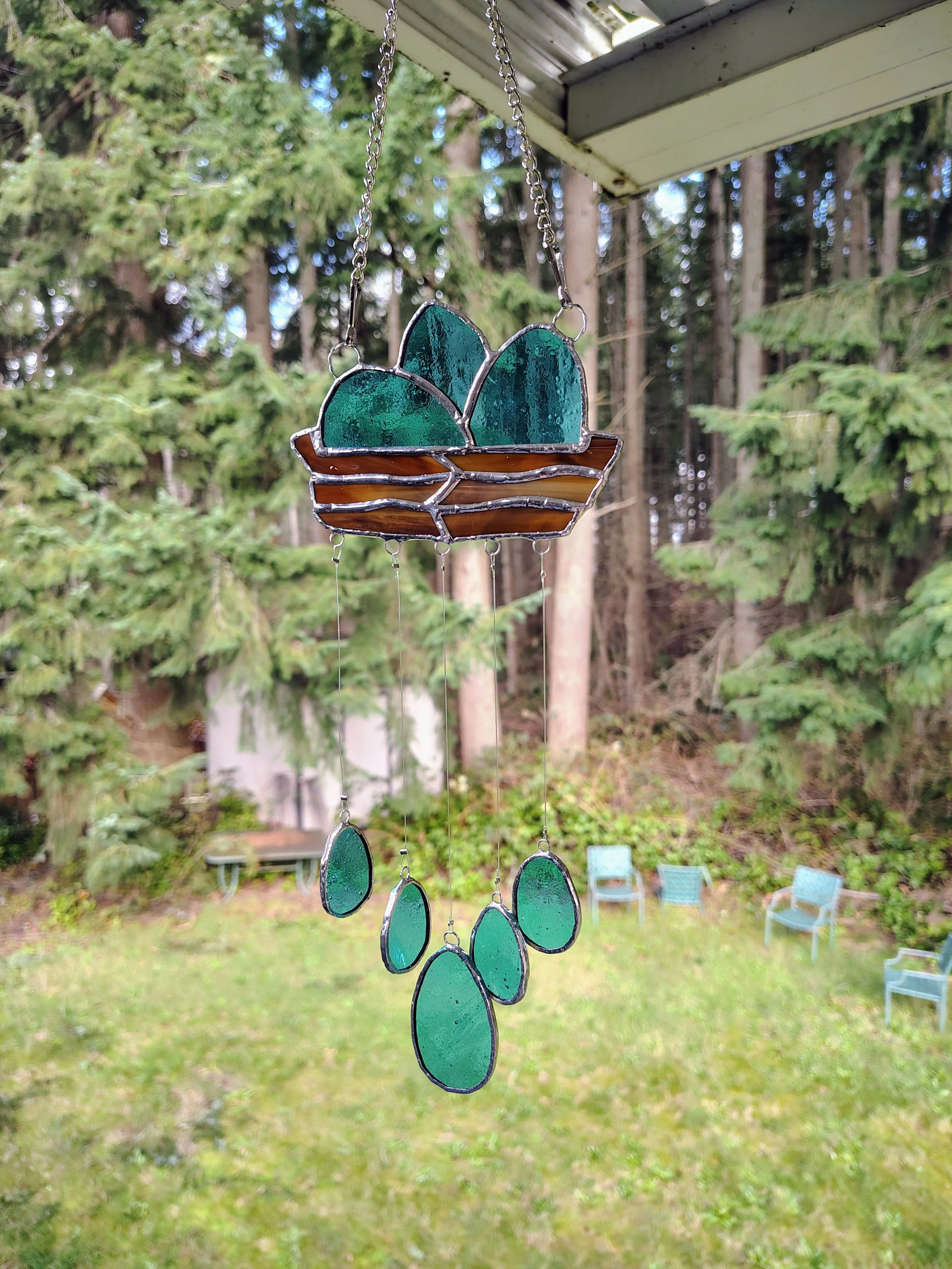 a nest windchime made of stained glass. brown nest includes blue eggs up top with blue eggs dangling