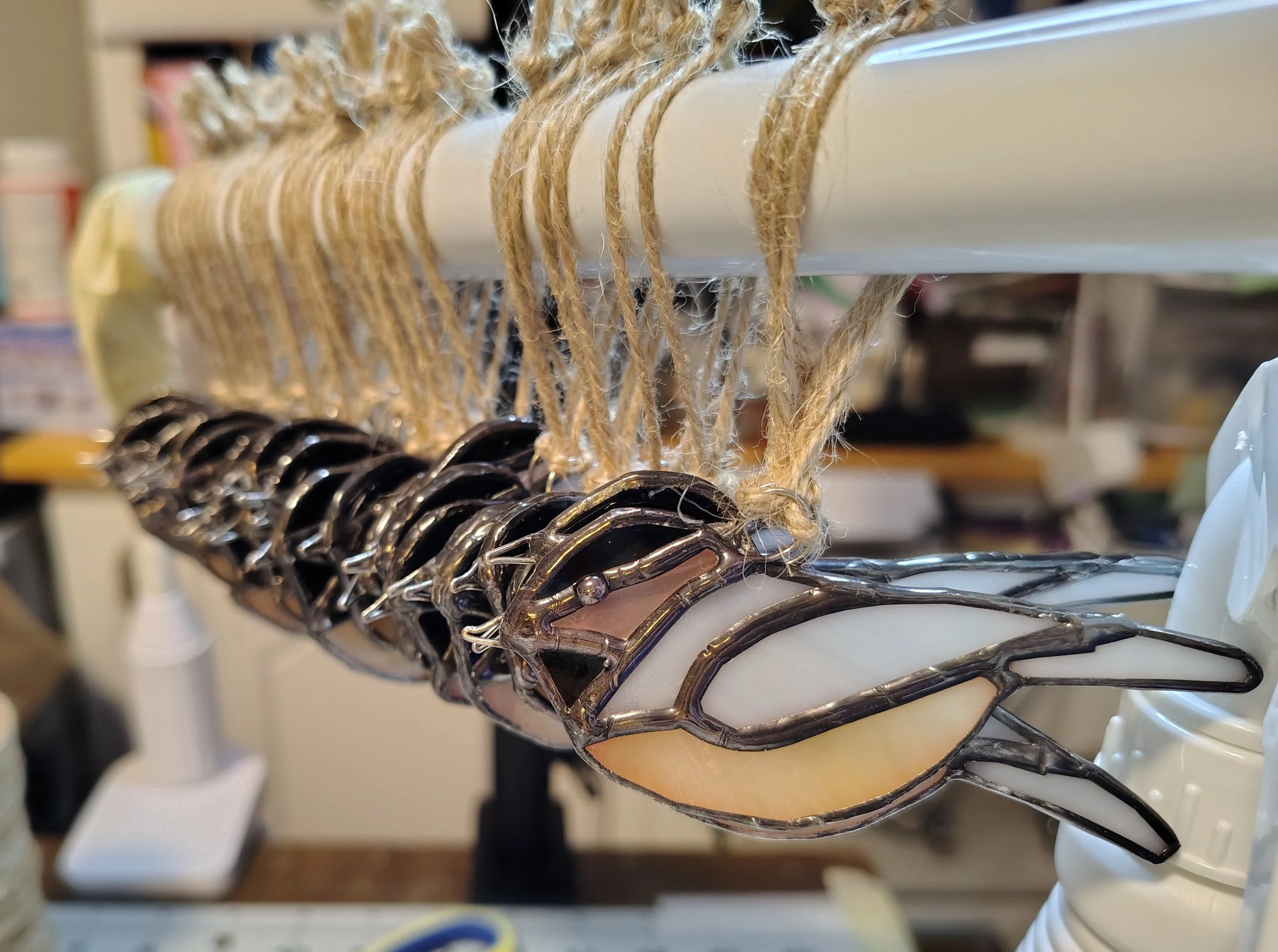 several small chickadee stained glass birds handing with jute ties