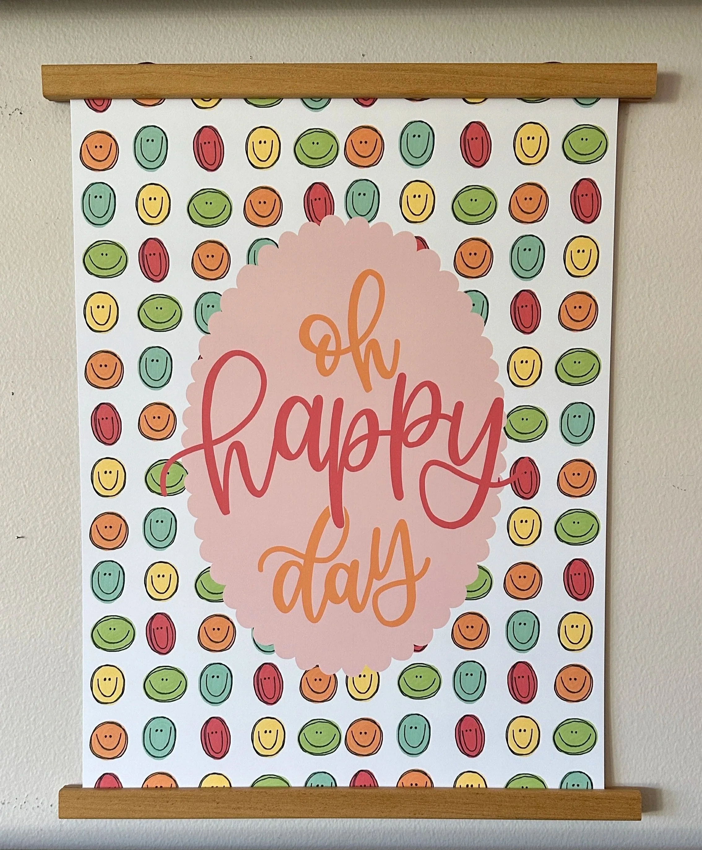 Colorful background with a repeating pattern of smiley faces in red, yellow, green, and orange. In the center, there is a pink cloud shape with cursive text that appears to say "Oh Happy Day!".