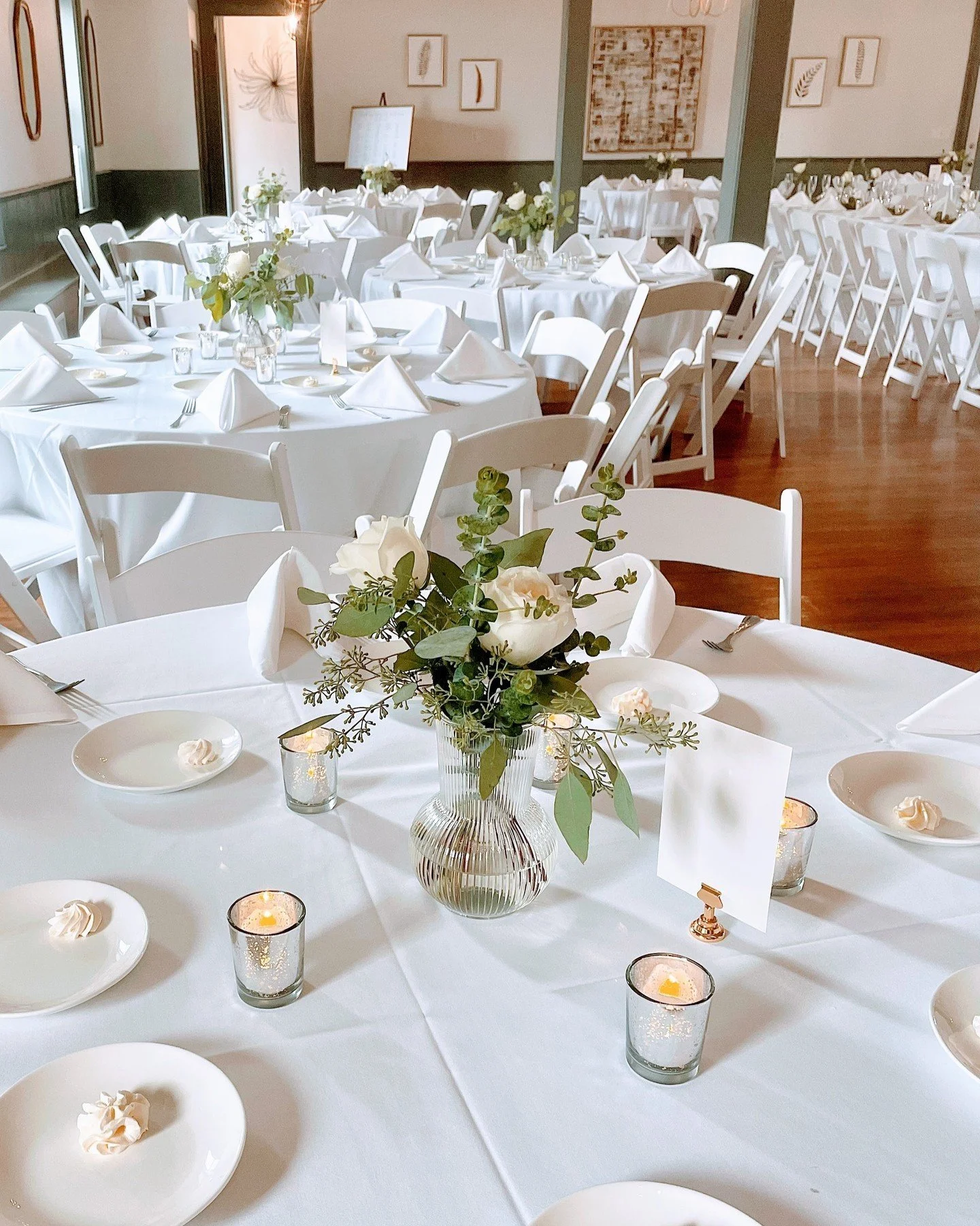 Wedding reception table with white tablecloths, floral centerpieces, and candles.
