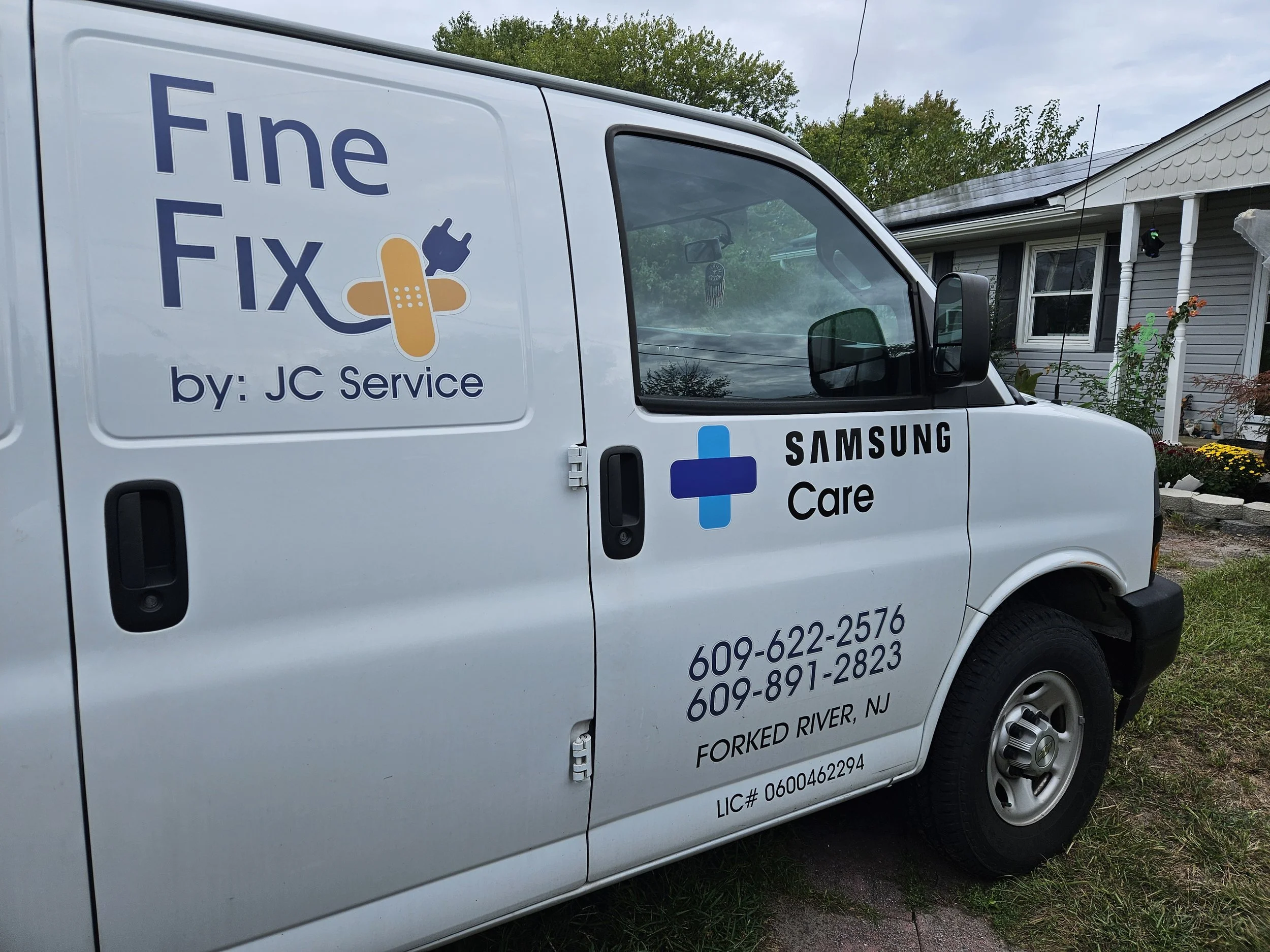 A white service van parked in front of a house with landscaping. The side of the van displays text including 'The Fix by: JC Service' and 'Samsung Care,' along with contact information and location details.
We are a Samsung authorized service center