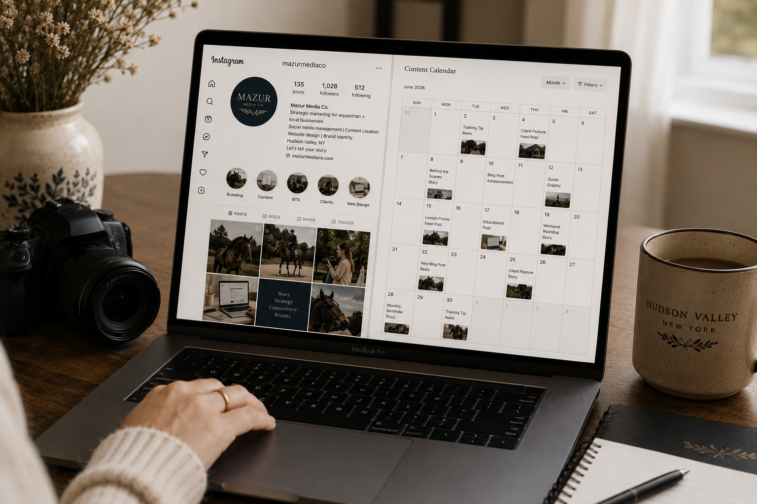 A MacBook Pro displaying an Instagram content calendar for June 2026, with a photographer's camera, a notebook, a pen, a potted plant, and a Hudson Valley New York mug on a wooden desk.