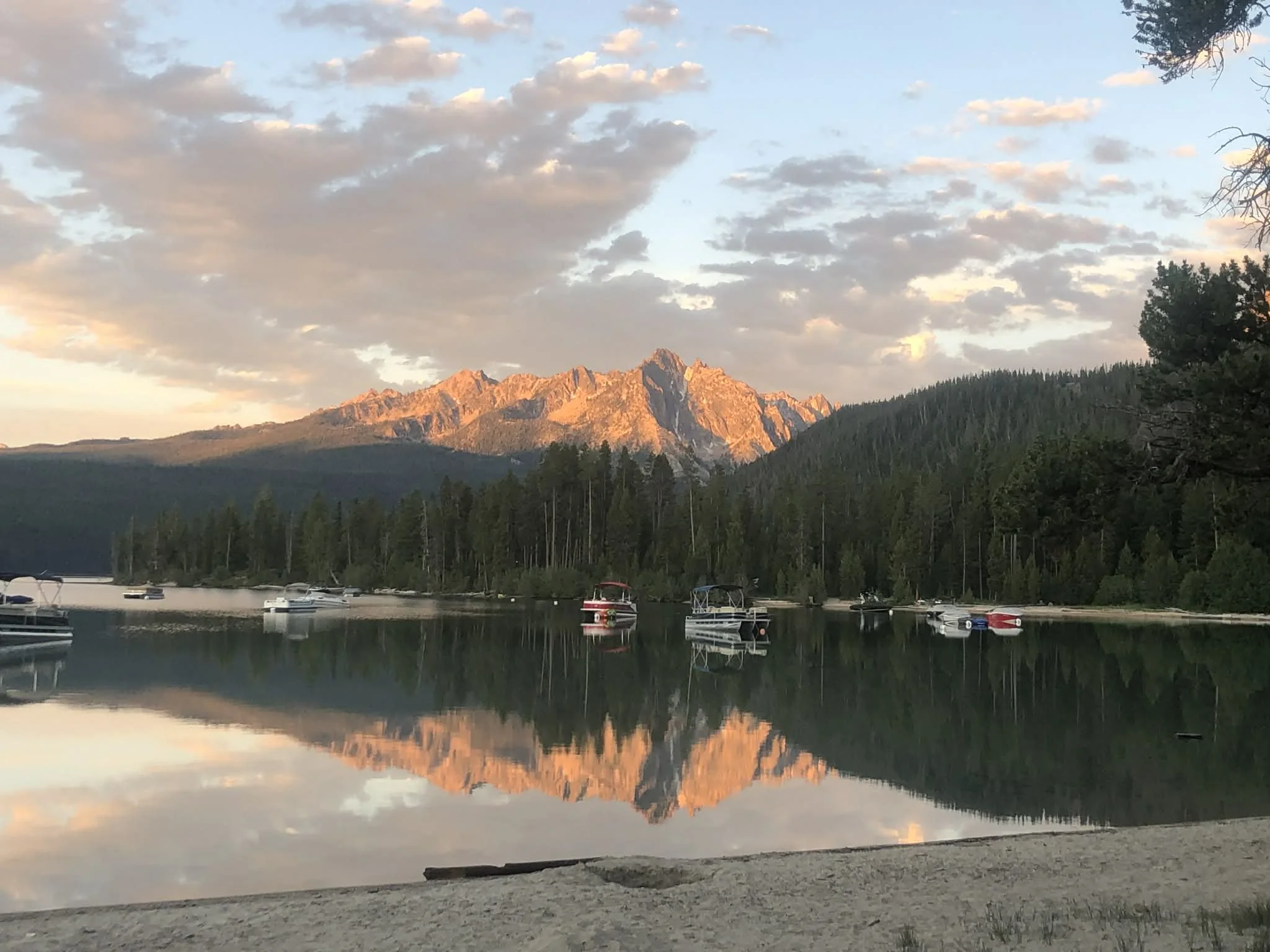 Scenic Idaho mountain lake at sunset reflecting calm water and rugged outdoor scenery.