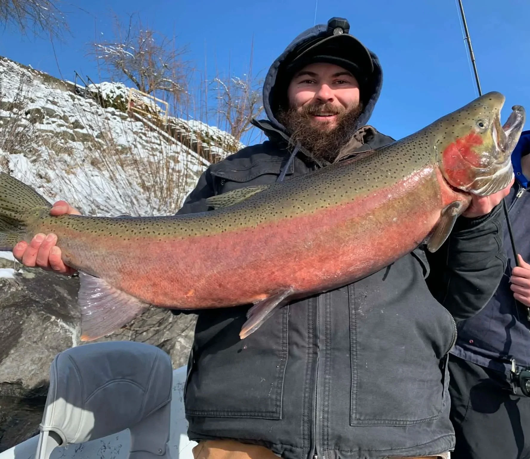 Angler holding a large rainbow trout during a winter fishing trip in the mountains.