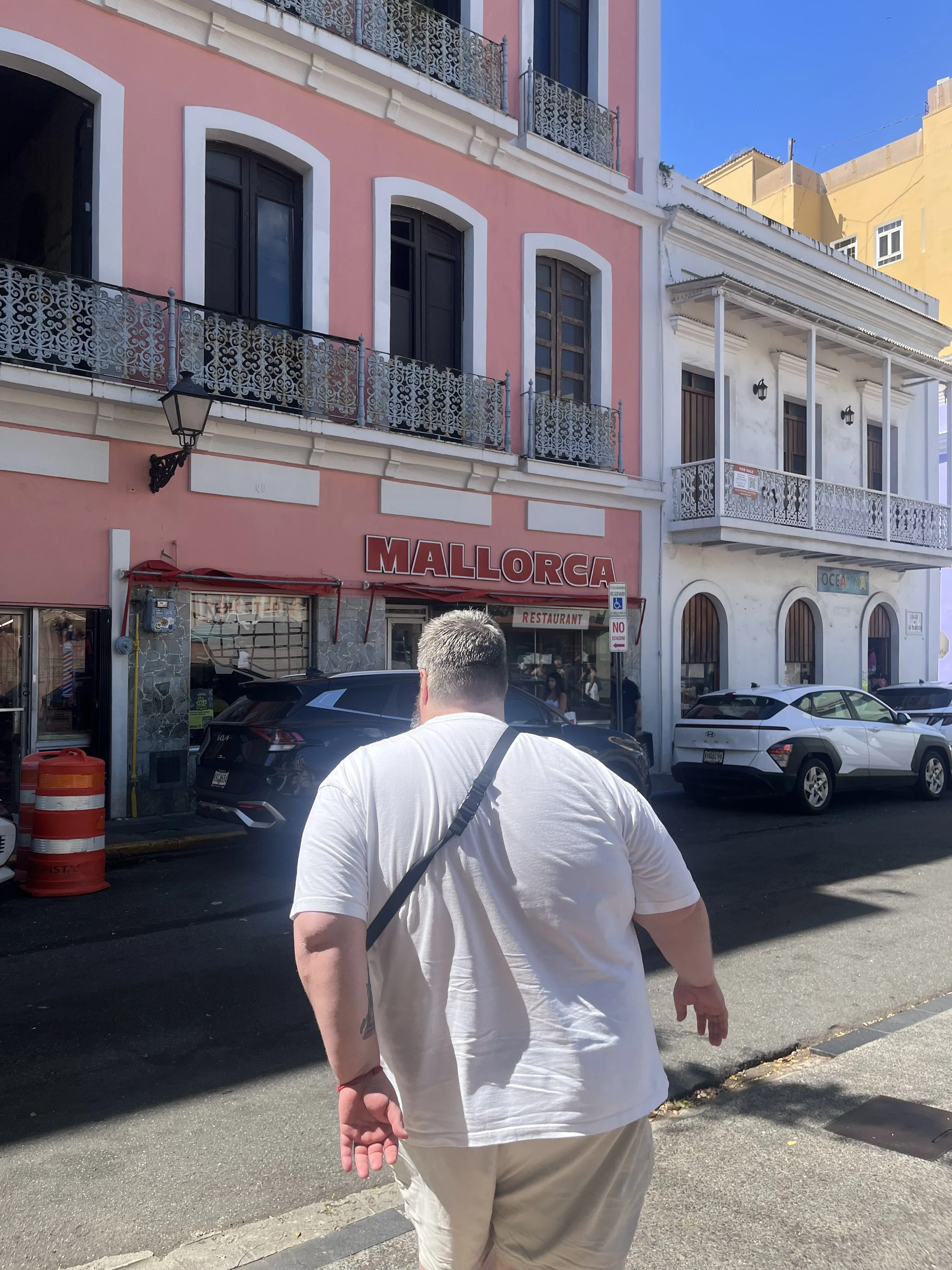 Man in white shirt walks toward Cafeteria Mallorca in San Juan, Puerto Rico