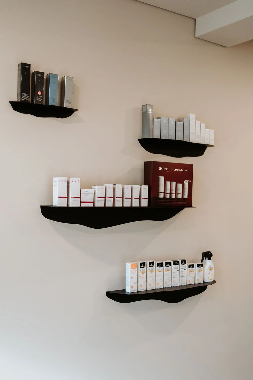 Wall-mounted black shelves holding various skincare or cosmetic products, with some boxes and spray bottles.