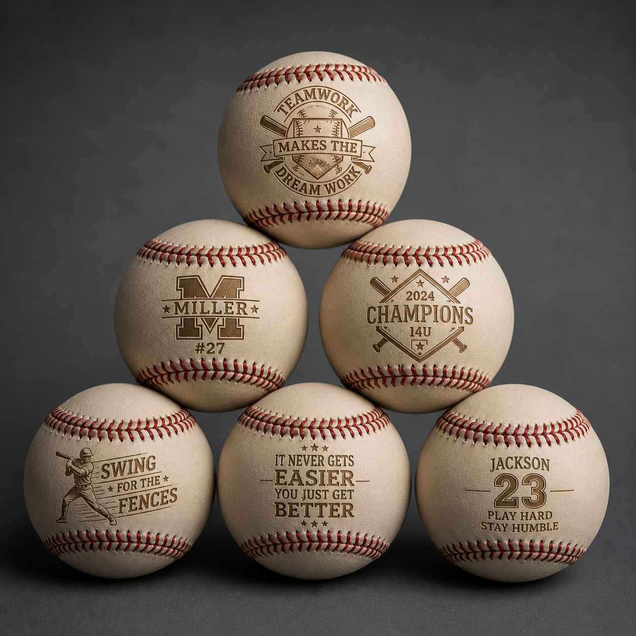 A pyramid of five baseballs with motivational and sports-themed inscriptions. The top baseball reads "Teamwork makes the dream work," the middle row includes "Miller #27" and "2024 Champions 14U," and the bottom row features "Swing for the fences," "It never gets easier you just get better," and "Jackson 23 play hard stay humble."