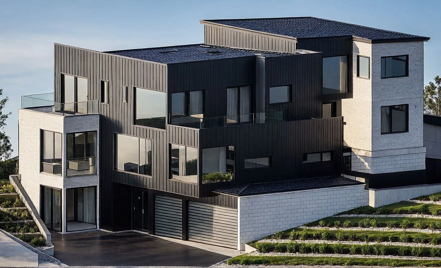 Modern multi-story house with black and white exterior, large windows, balconies, and landscaped yard