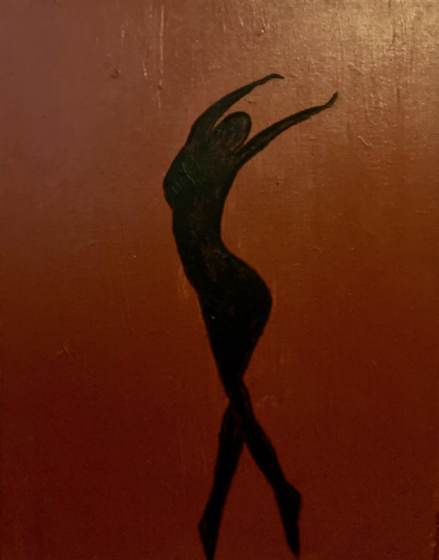 A silhouette of a woman with long hair, stretching her arms above her head, against an orange background.