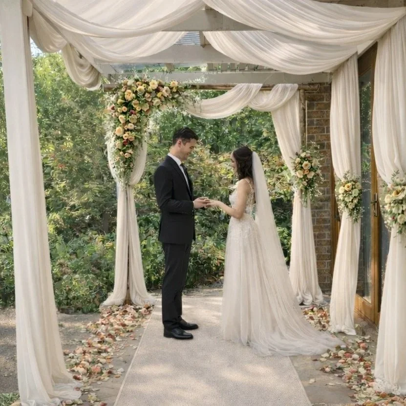 A bride and groom exchanging vows under a decorated floral arch at an outdoor wedding ceremony.