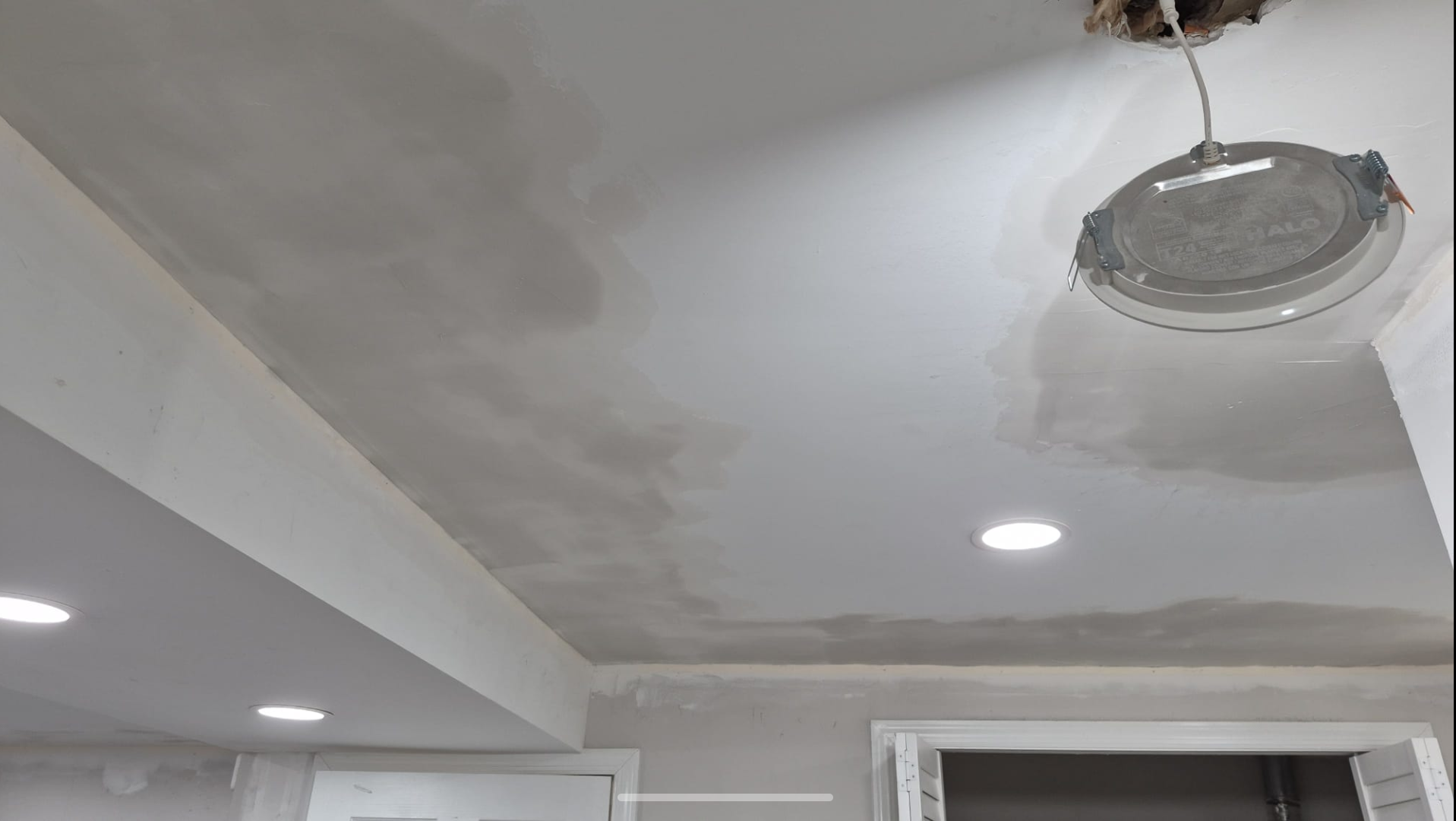 Ceiling with newly painted white drywall, recessed lighting, and an open electrical fixture with wires.