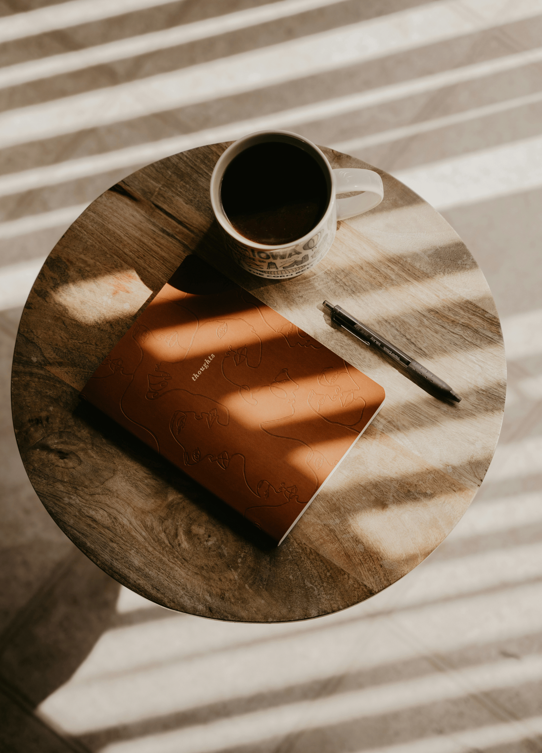 A journal and coffee resting on a wooden table with soft morning light, representing mindful routines and intentional living.
