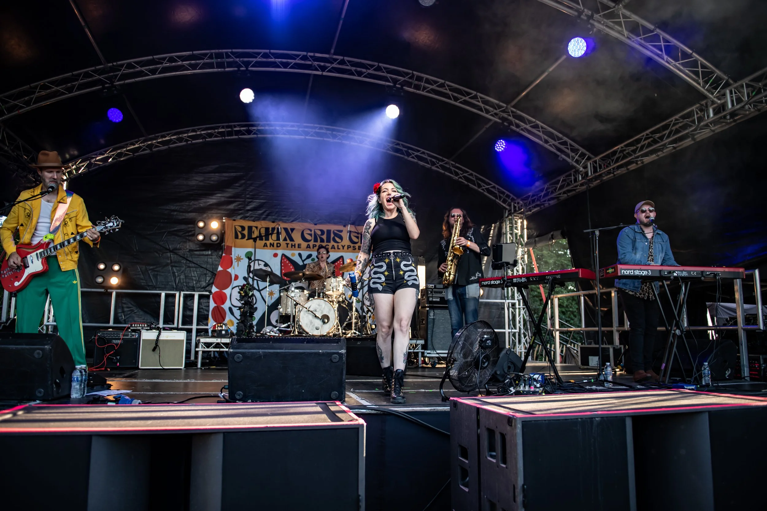 Lead vocalist and band performing live at Cornbury Festival. High-energy rock concert photography with colourful stage lighting by Two Finger Media.