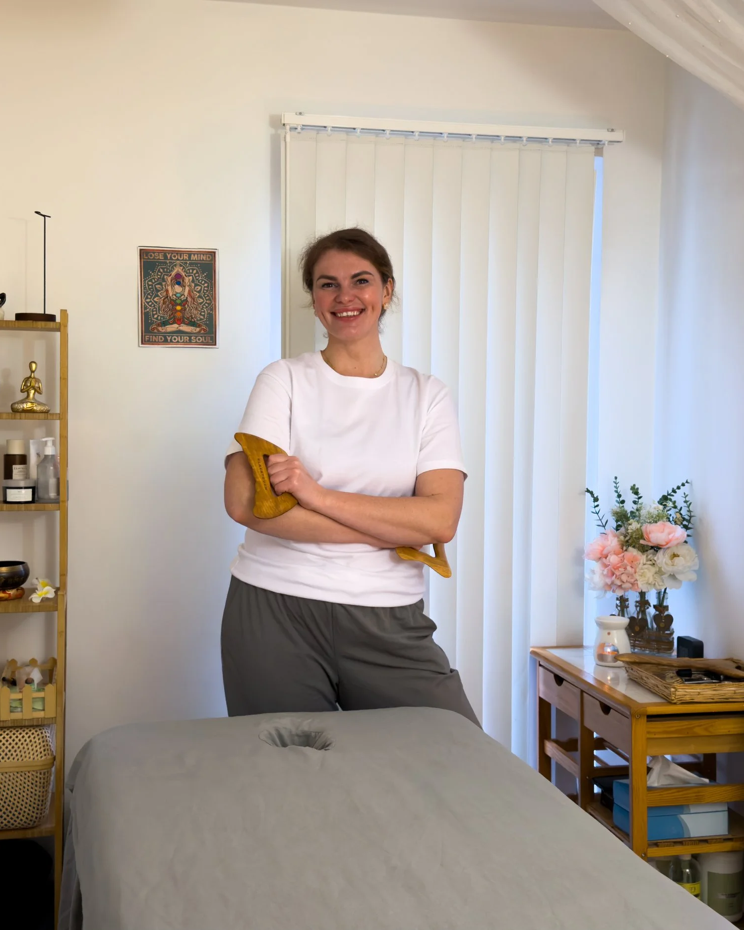 Holistic massage therapist at inSoul Wellness in Greenwich holding a wooden massage tool in a calming treatment space, offering massage therapies including deep tissue, lymphatic drainage, pregnancy and facial sculpting treatments.