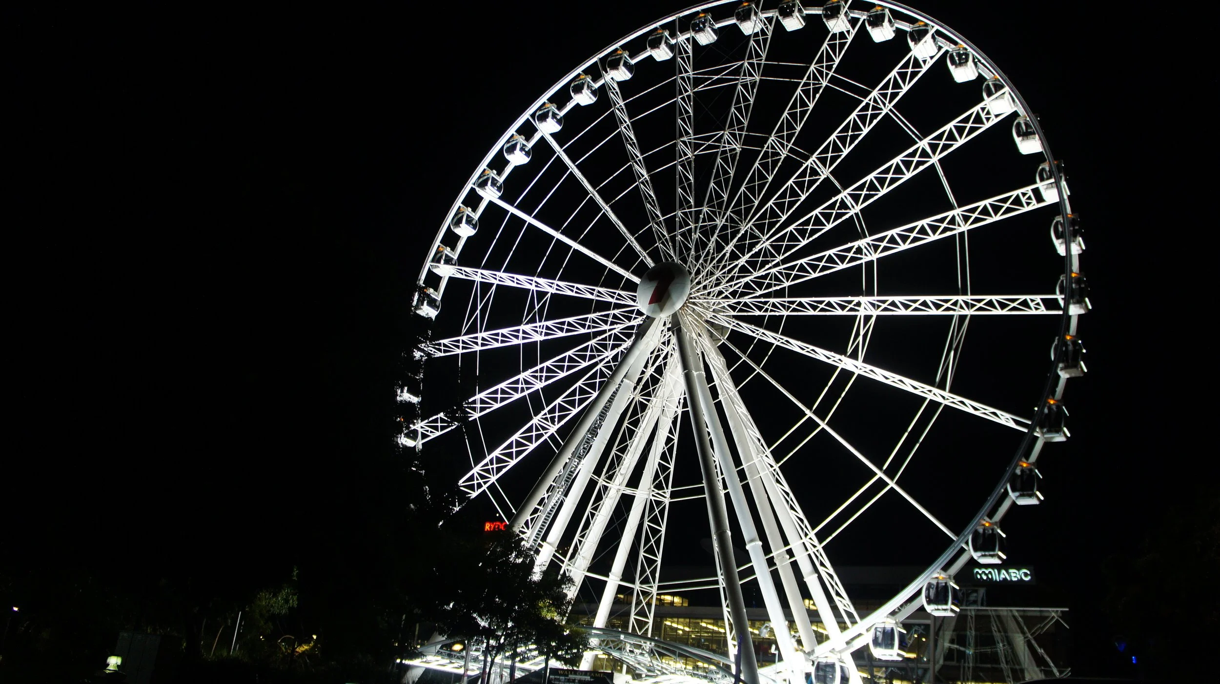 Night view of a brightly lit Ferris wheel against a dark sky.