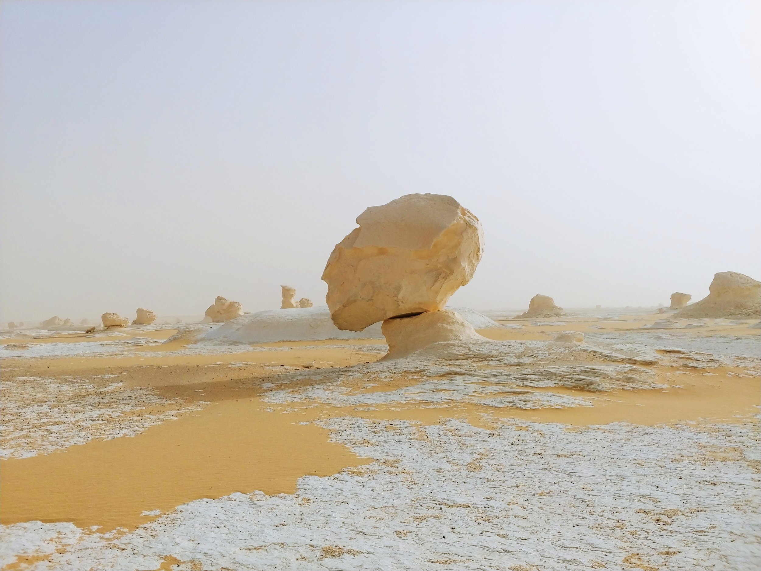 Large light-colored rocks in a desert landscape with a hazy sky in the background