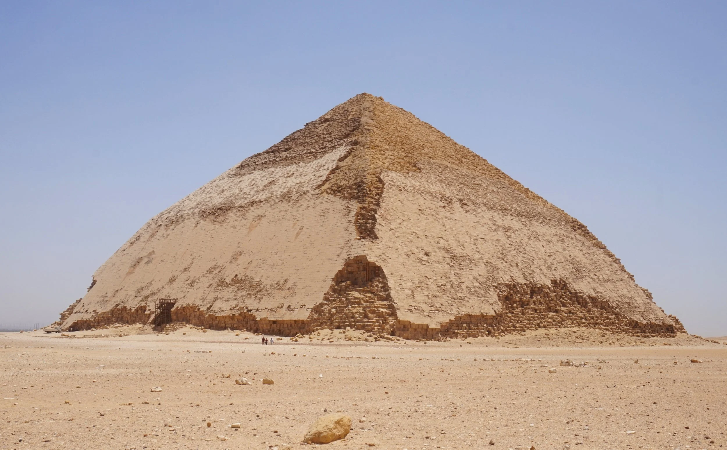 The Great Pyramid of Giza in Egypt, a large ancient stone pyramid structure with a flat top, situated in a sandy desert with a clear blue sky in the background.