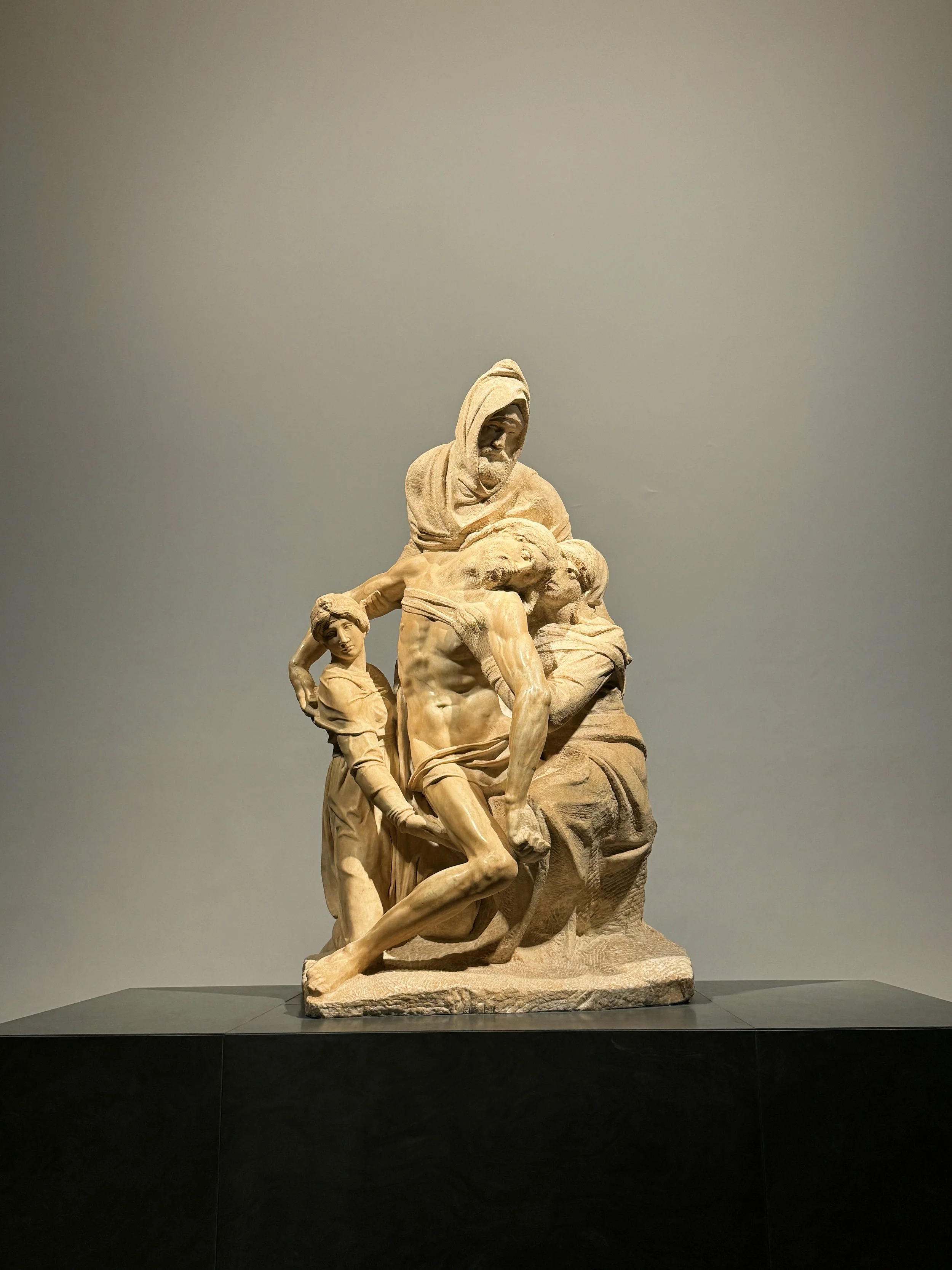 Stone sculpture depicting Jesus Christ carrying the cross, with a woman and a young girl.