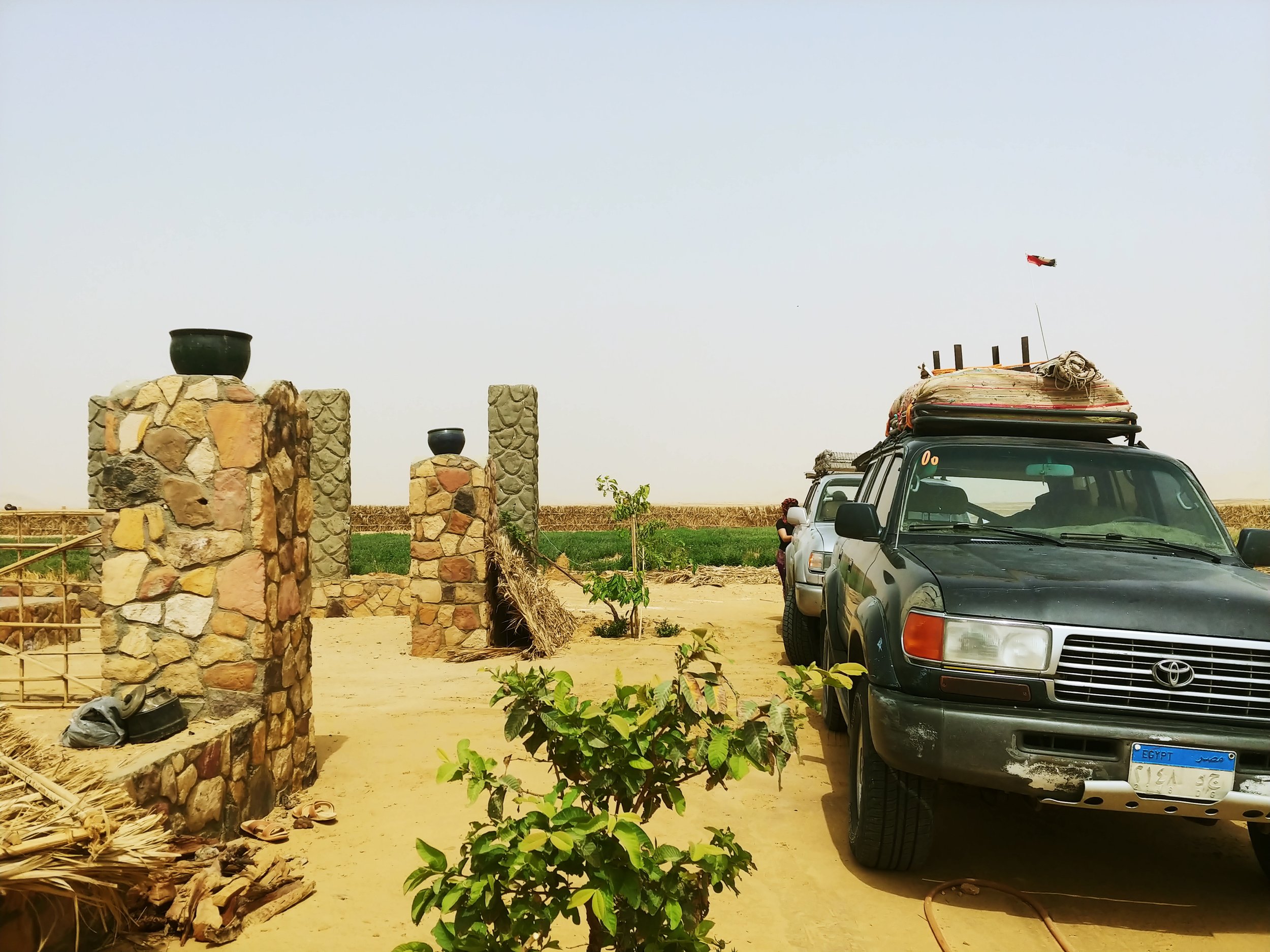 A vehicle parked in front of a construction area with stones, potted plants, and a blue sky.