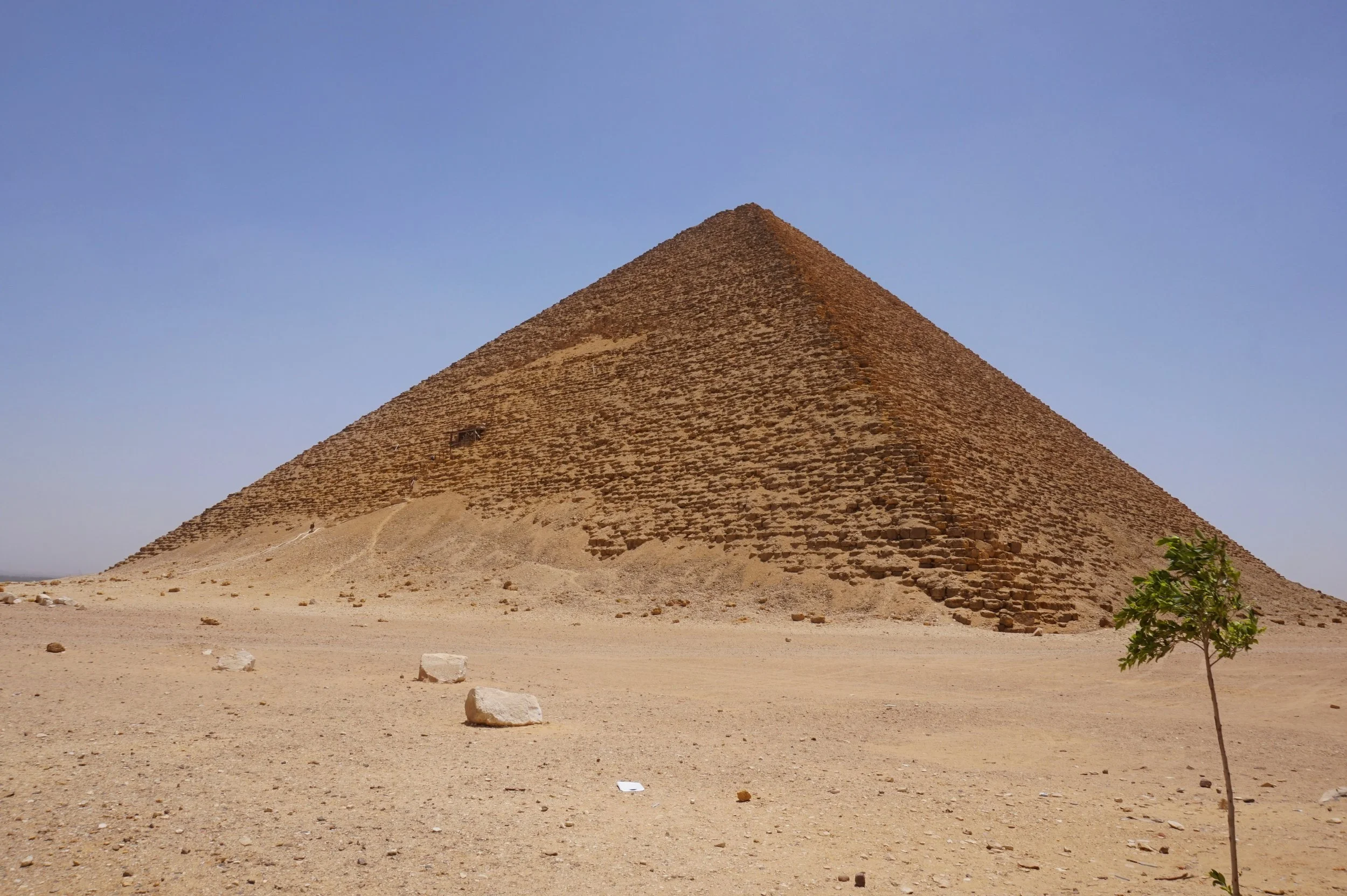 The Great Pyramid of Giza in Egypt, a large ancient stone pyramid with a sandy surrounding landscape and a clear blue sky.