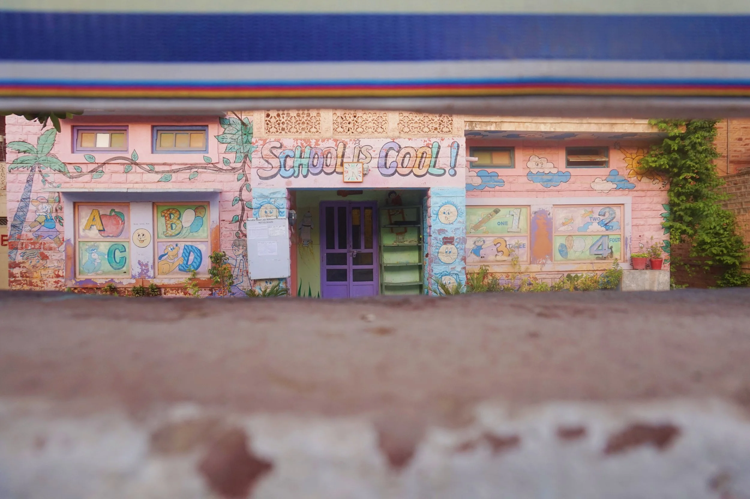 Colorful children's school with painted murals, including the phrase 'School is Cool!', windows, and vibrant decorations.