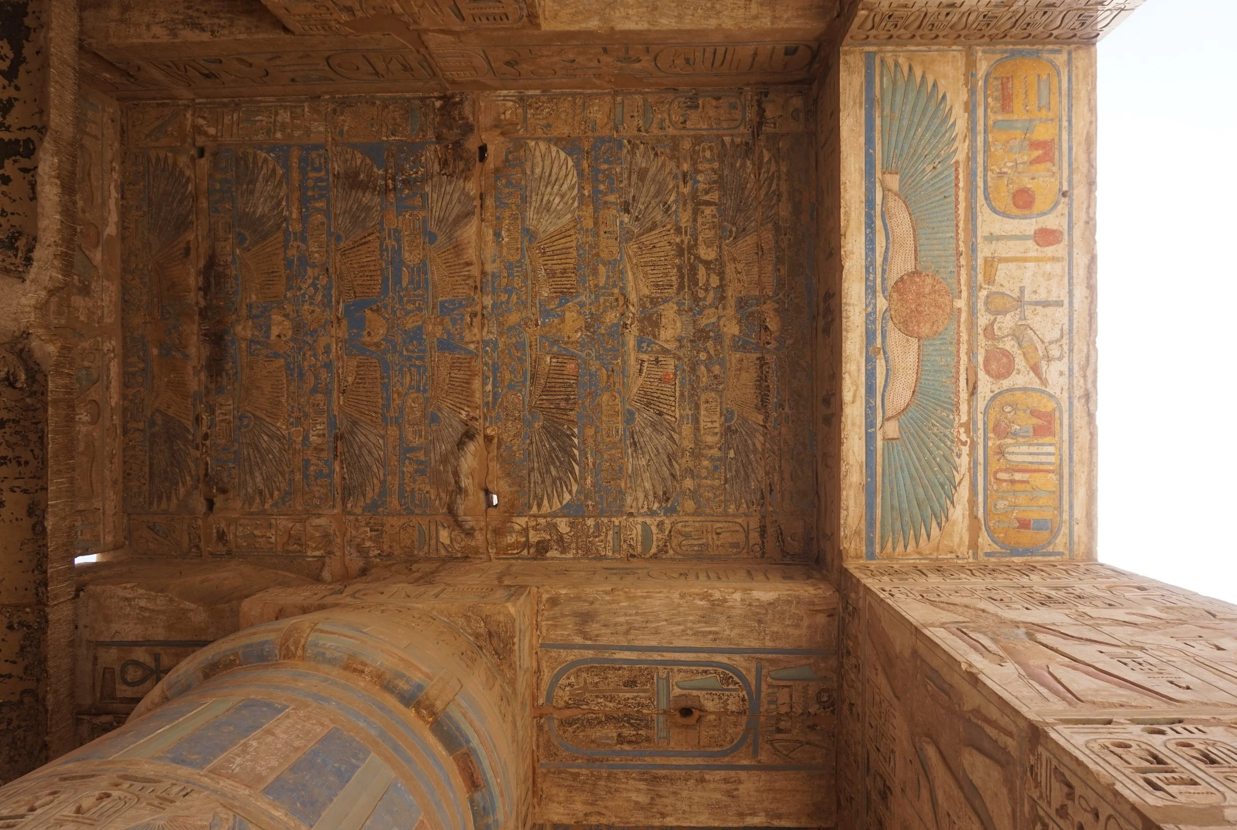 Ancient Egyptian tomb interior with colorful hieroglyphic paintings and carvings on walls and columns.