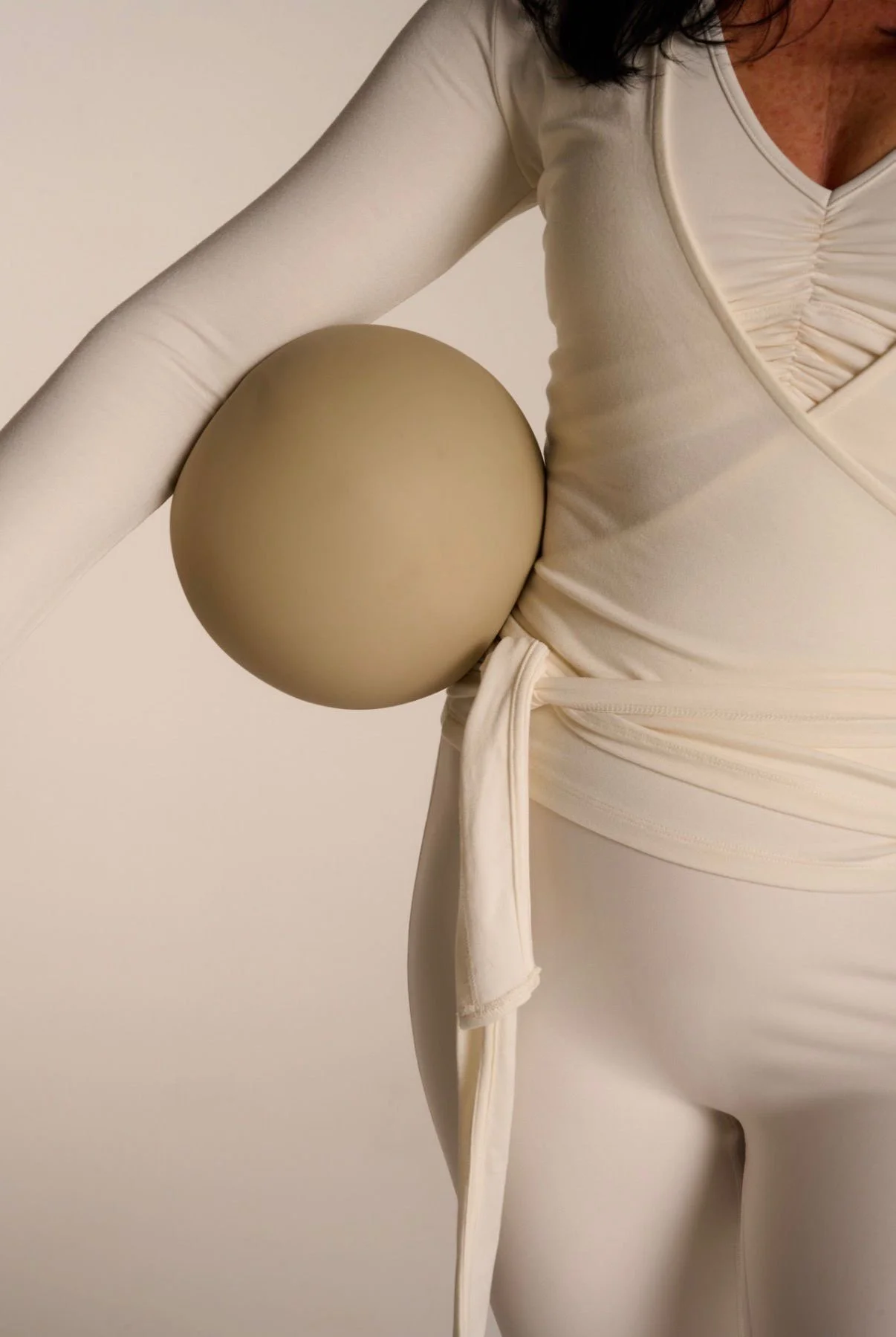 Close-up of a sculpture of a woman in a cream-colored dress, with a large spherical shoulder accent and flowing fabric details.
