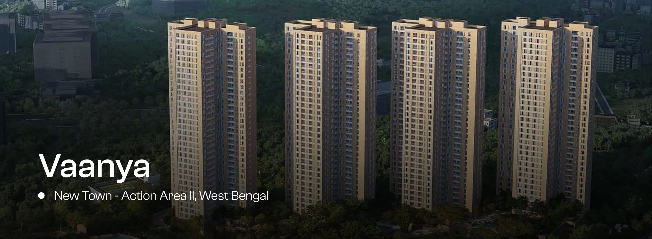 Aerial view of tall residential apartment buildings in Vaanya, a new town in Action Area II, West Bengal, with greenery and other buildings in the background.