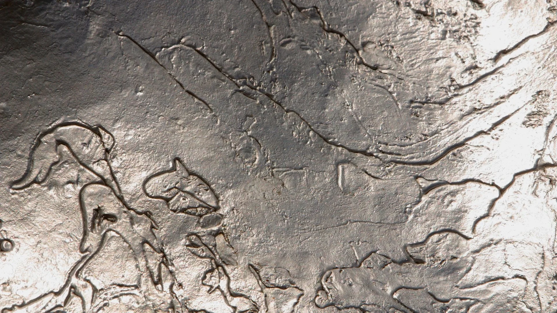 Surface rocheuse grise avec des fissures et des reliefs, aspect rugueux et craquelé.
