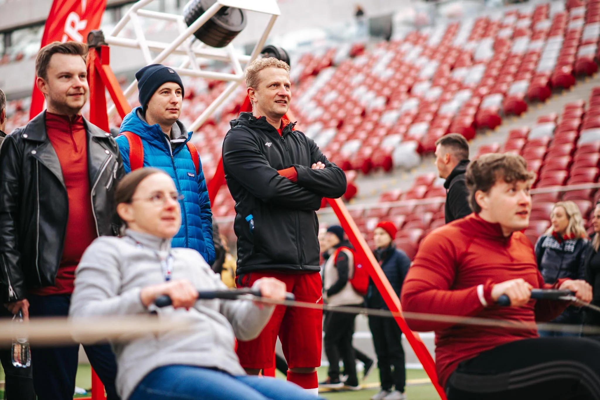 Group of spectators watching a football game at a stadium with seats in the background.