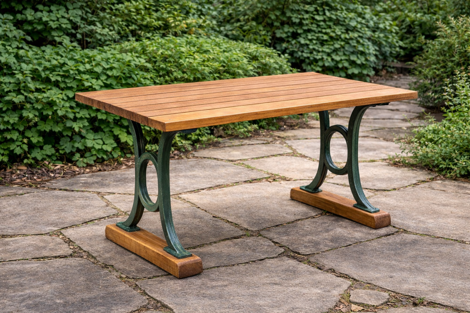 Wooden outdoor bench with green metal legs on a stone pathway surrounded by greenery