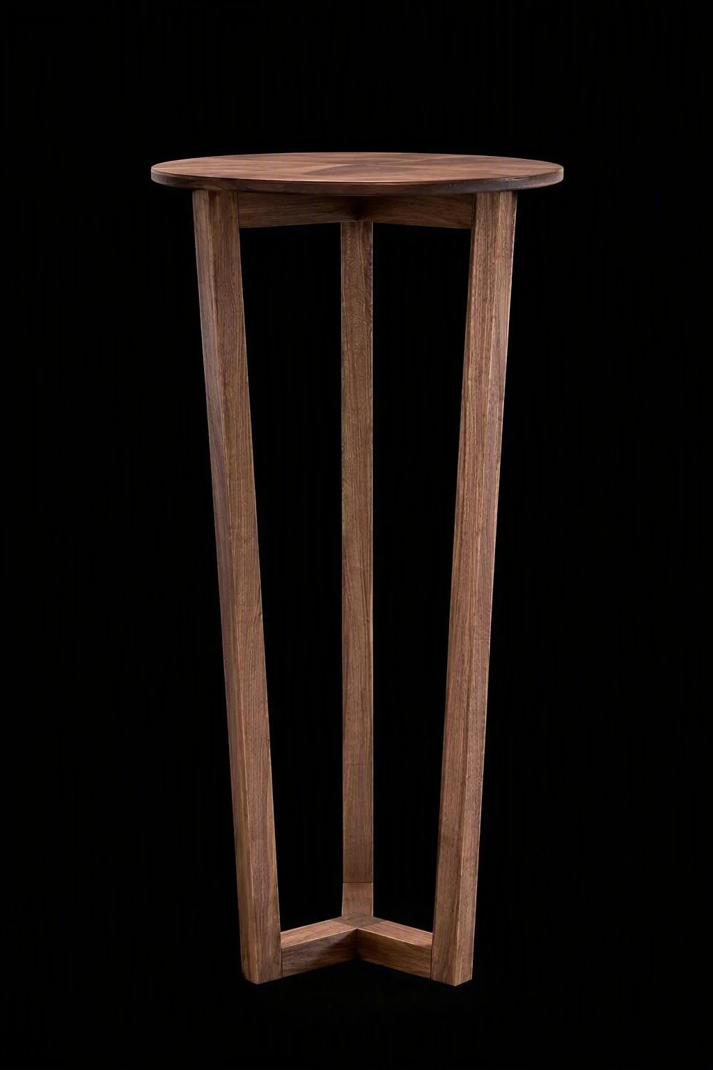 A tall wooden plant stand with a circular top and three angled legs against a black background.