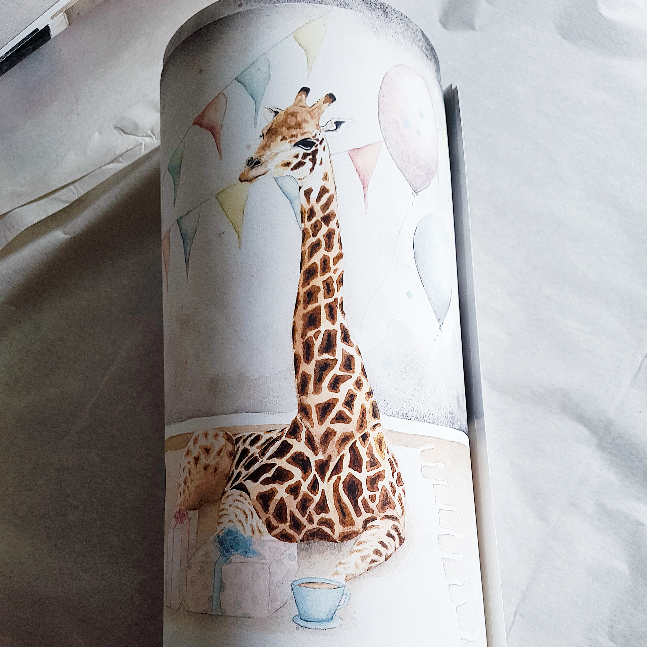 Vitt papper med tecknad giraff och ballonger i bakgrunden.