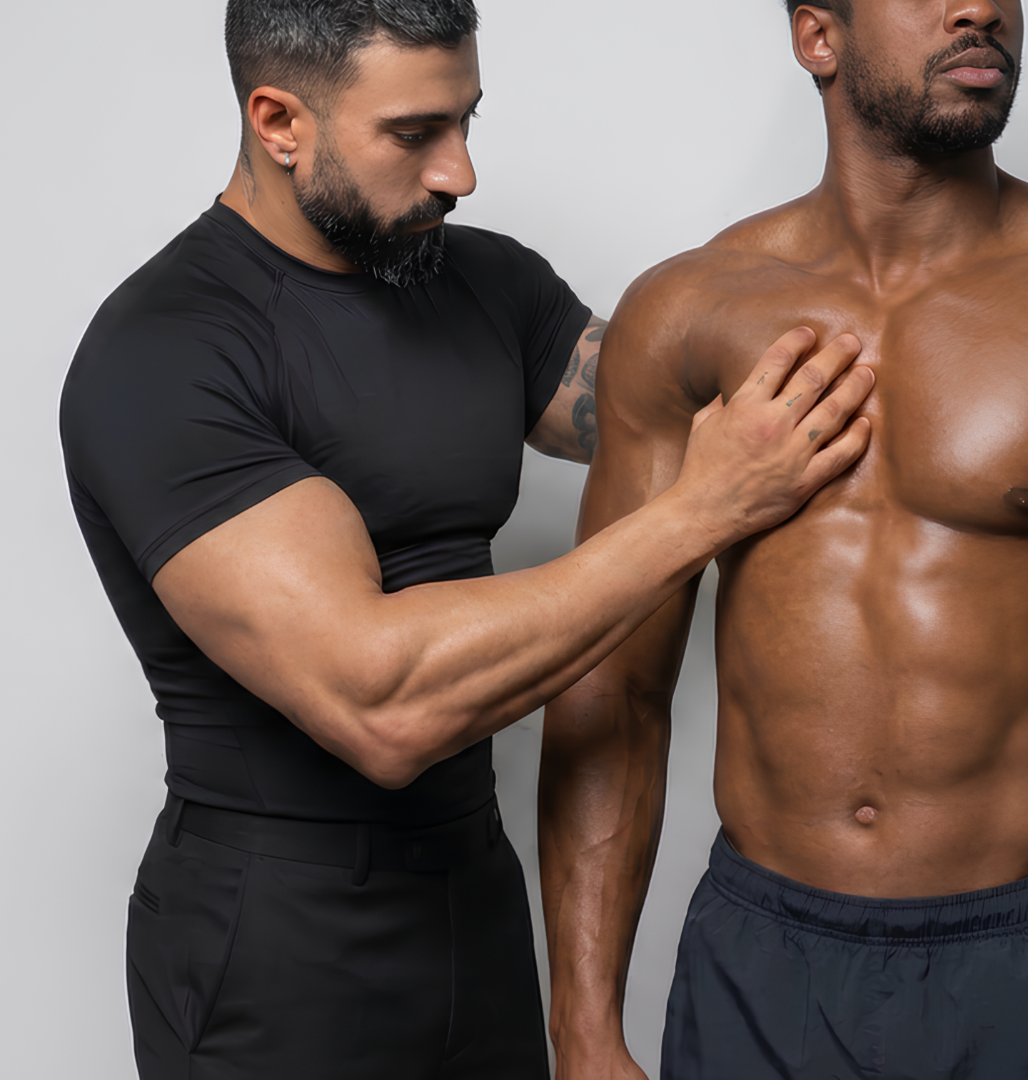 A shirtless man with a muscular chest is being examined by a healthcare professional who is checking his shoulder and chest area.