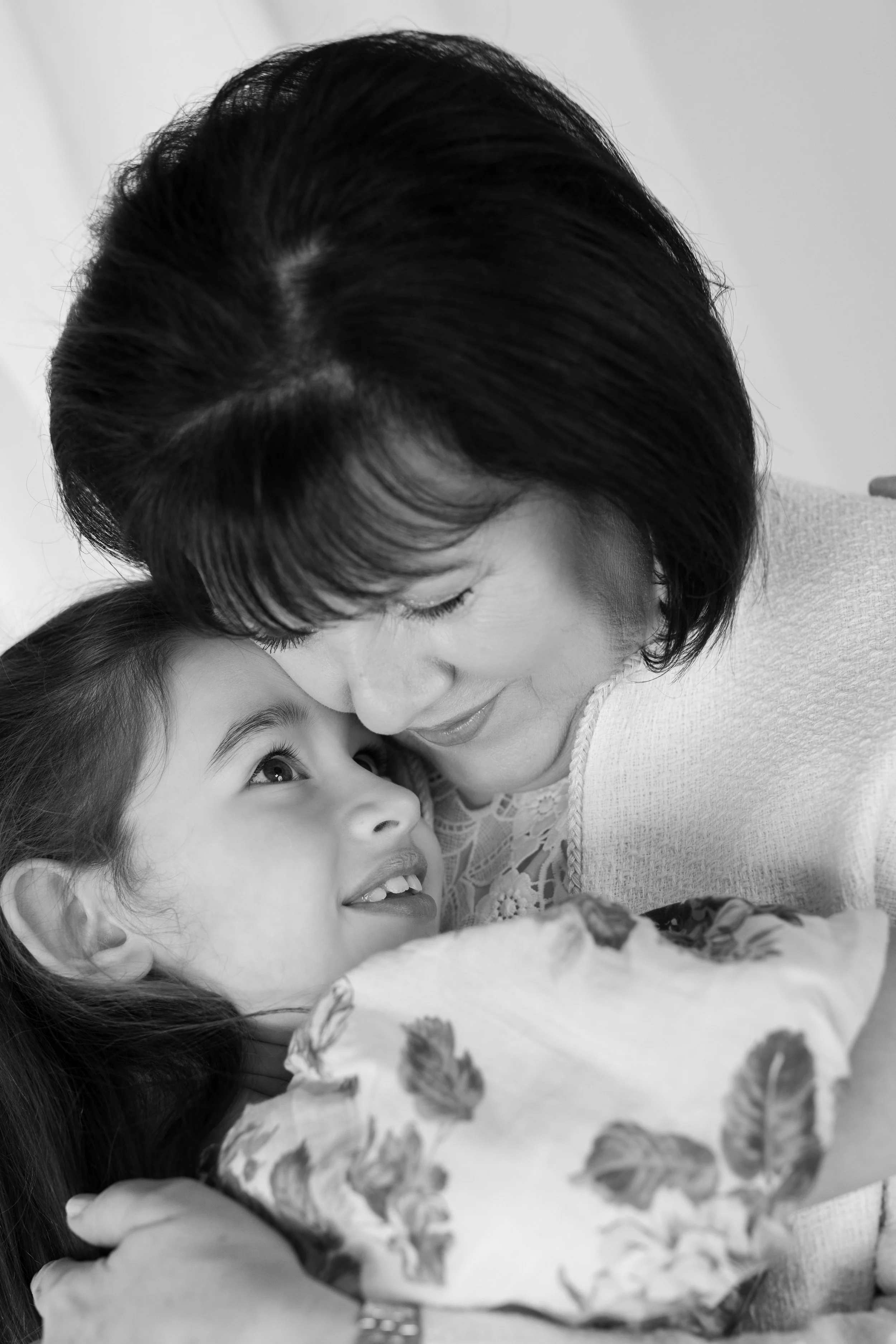 A woman and a young girl sharing an affectionate moment, with the woman leaning in to kiss the girl on the cheek, both smiling and showing closeness.